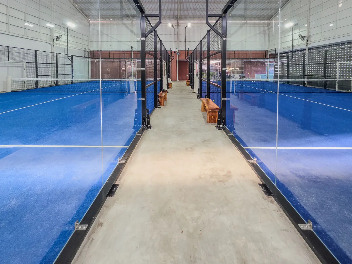 Indoor padel courts with blue surfaces and glass walls